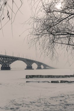 Klasik kış manzarası. Donmuş bir nehirde sisli bir köprü.