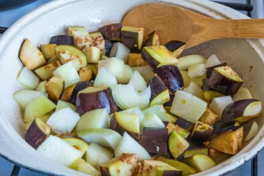 Patlıcan ve soğan büyük bir kırsal tavada kızartılır..