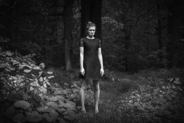 Karanlık bir ormanda çekici, neşeli bir genç kadın.