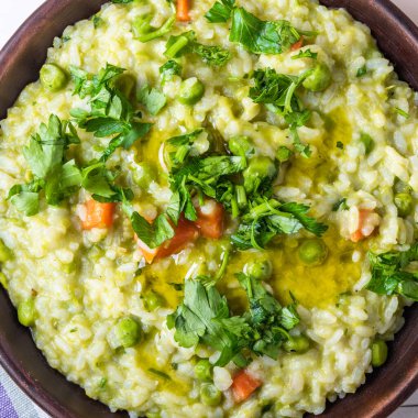 Bezelyeli, havuçlu ve maydanozlu geleneksel İtalyan vejetaryen risotto.