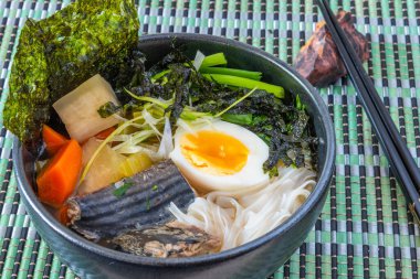 Japon balık çorbası, pilav eriştesi, turp ve yumurta bambu peçete ve çubuk üzerinde bir kase - balık ramen