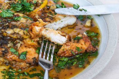 Kızarmış tavuk göğsü, limon dilimleri ve beyaz tabakta lezzetli bir sos.