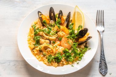 Hafif ahşap arka planda bir tabakta deniz mahsullü risotto - İtalyan mutfağı.