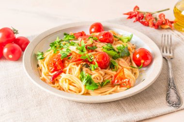 Makarna al pomodoro - kiraz domatesli spagetti ve maydanozu kırsal tarzda yakın bir tabakta.