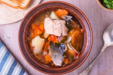 Somon çorbası. Kil tabakta patates, havuç ve domates ile kalın balık çorbası. Üst görünüm.