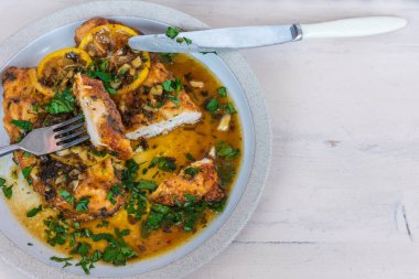 Kızarmış tavuk göğsü ve limon dilimleri ve lezzetli sos masanın üzerinde peçete, çatal ve bıçakla birlikte, üst manzara, kopyalama alanı