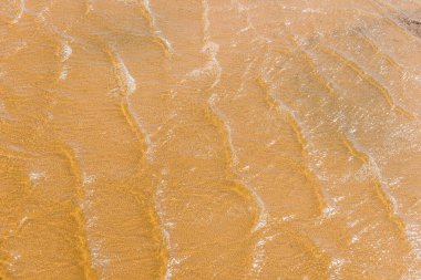 Kristal berrak suyun altındaki sarı kumlu taban, çevre dostu tatil kavramı.