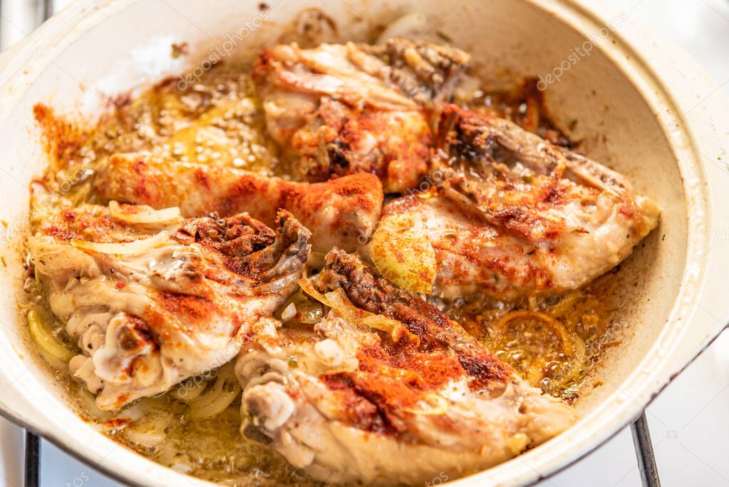 Chicken stew in a pan with onions and tomato paste close-up