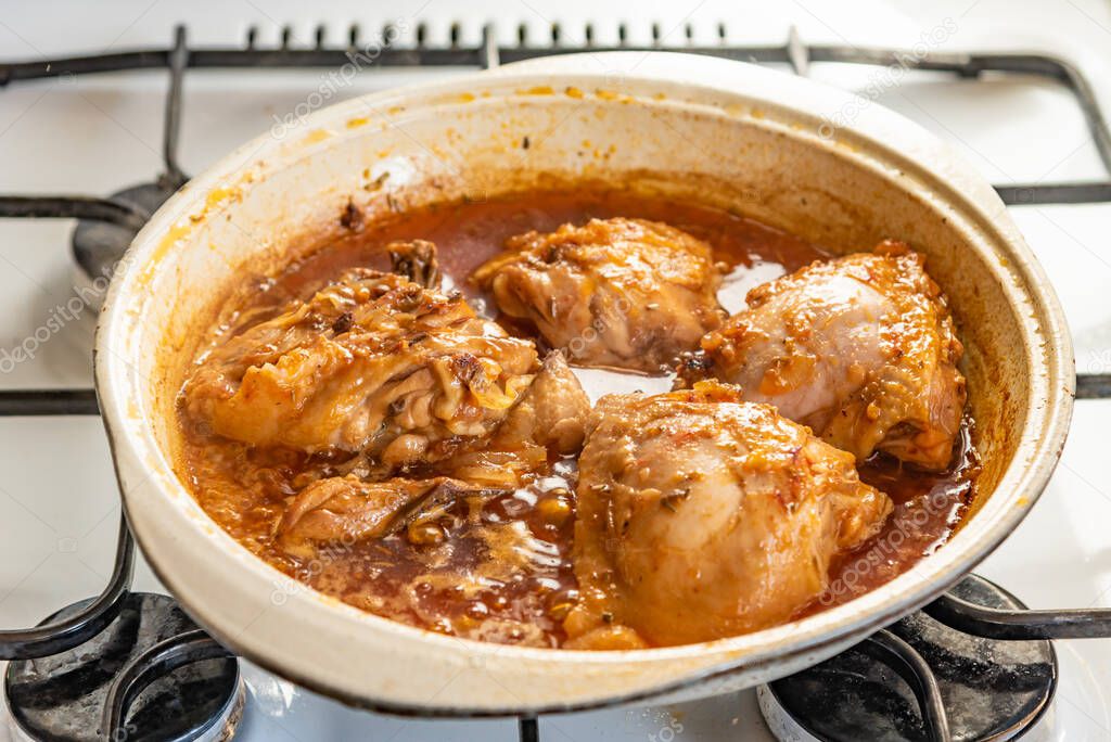 Chicken stew in a pan with onions and tomato paste close-up