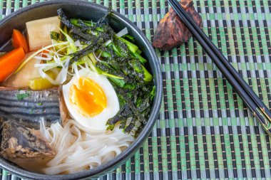 Japon balık çorbası, pilav eriştesi, turp ve yumurta bambu peçete ve çubuk üzerinde bir kase - balık ramen