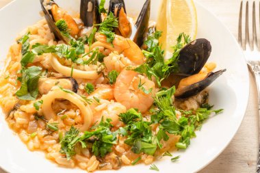 Açık ahşap bir tabakta deniz mahsullü risotto, yakın plan İtalyan mutfağı.