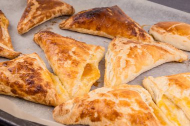 Pişirme kağıdının üzerindeki puf böreğinin lezzetli altın üçgenleri.