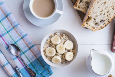 Kahvaltıda muzlu yulaf ezmesi ve sütlü kahve. Üst manzara, açık kırsal arka plan.