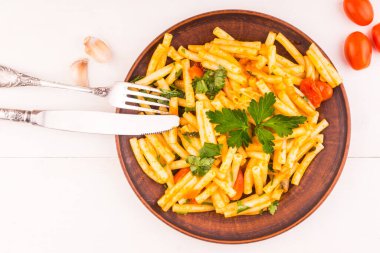 Kırsal arkaplandaki kil tabaktaki kırmızı soslu makarna. Domatesli vejetaryen tarifi.