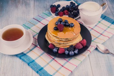 Akçaağaç şurubu ve böğürtlenli krep ve ahşap bir kırsal masada çay - üst manzara