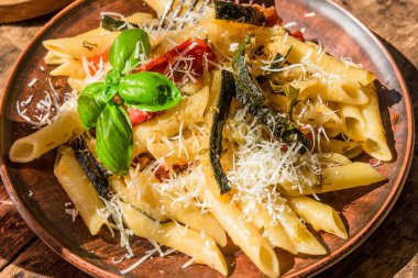 Klasik İtalyan makarnası, kabaklı ve domatesli. Kır tabağında, kır manzaralı.