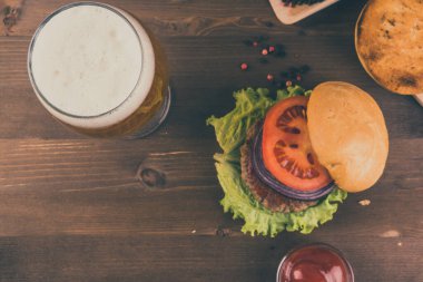 Ev yapımı hamburger ve ahşap bir masada bir bardak bira.