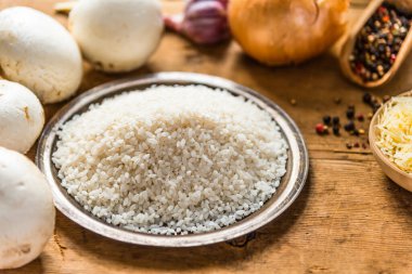 Kırsal ahşap bir masada mantarlı risotto için malzemeler.