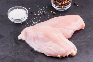 Koyu arkaplanda baharatlı çiğ tavuk filetosu.