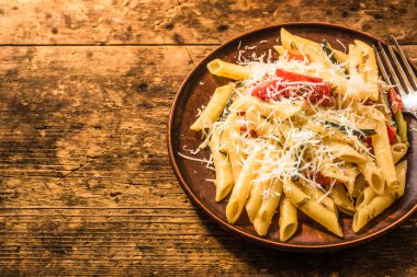 Klasik İtalyan makarnası, kabaklı ve domatesli. Kırsal bir masada kil tarakta. Üst manzara, bir tarif için kopyalama alanı.