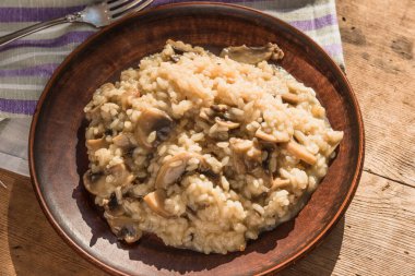 Geleneksel İtalyan yemeği. Mantarlı risotto. Eski ahşap bir tabakta.