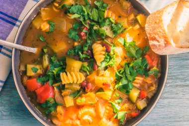 Geleneksel sebze çorbası makarna ve doğranmış yeşil maydanoz kırsal ahşap bir masa üzerinde peçeteyle yakın plan, güneşli bir gün - üst manzara, bir tarif için kopyalama alanı