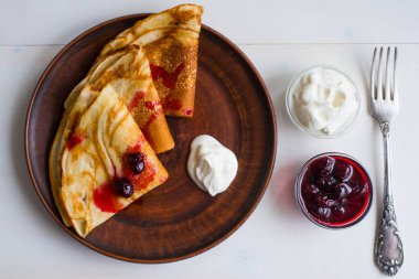Yoğurt ve reçelli krepler kil tabakta ve kırsal arka planda
