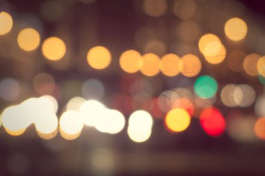 Gece şehir sokaklarının arka planında parlak araba farları var.