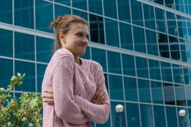 Genç ve güzel bir kadın iş merkezinin arka planında donuyor.