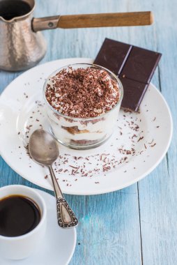 Ev yapımı İtalyan tatlı tiramisusu, rendelenmiş çikolatalı bir bardak, ve kırsal bir masada bir fincan kahve, kopyalama alanı.