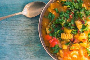 Geleneksel sebze çorbası makarna ve doğranmış yeşil maydanoz kırsal ahşap masa manzaralı bir tabakta yakın plan, bir tarif için yer kopyalama