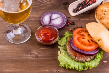 Lezzetli ev yapımı hamburgerle yarısı boş bira bardağı