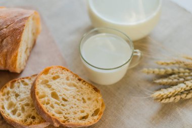 Sürahi ve bir bardak süt, ahşap kırsal arka planda taze pişmiş ekmek.