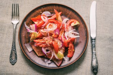 Kırsal bir çömlek üzerinde domates ve kırmızı soğan salatası.