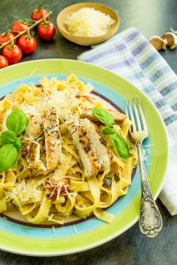 Geleneksel İtalyan tagliatelle makarnası, büyük bir tabakta vişneli domates ve kızarmış tavuk.