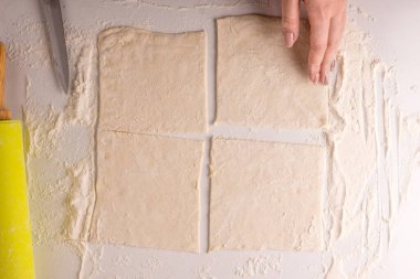 Kadın böreği kare şeklinde kesiyor.