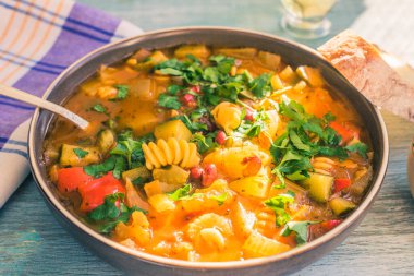 Makarna ve yeşil maydanozlu sebze çorbası boyalı ahşap masa üzerinde yakın plan bir peçeteyle yakın plan yeşil maydanoz.