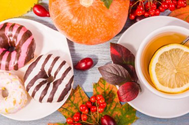 Limonlu çay ve renkli çörekler, balkabağı ve böğürtlenli sonbahar yaprakları - sonbahar konsepti