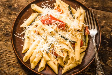 Klasik İtalyan makarnası, kabaklı ve domatesli. Kır tabağında, kır manzaralı.