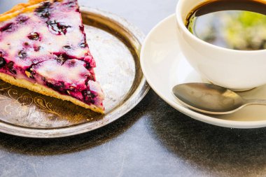 Siyah üzümlü ev yapımı tart ve koyu arkaplanda bir fincan kahve.