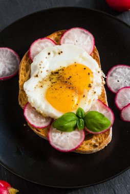 Yağda yumurta ve siyah tabakta turplu lezzetli bir sandviç.