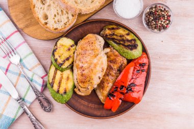 Kızarmış tavuk fileto ve ızgara sebzeler ahşap bir tabakta - üst manzara