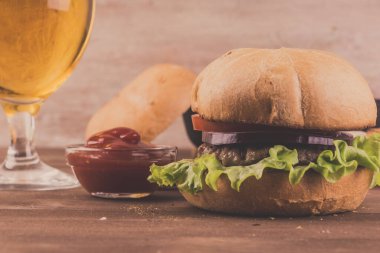 Ev yapımı hamburger, ızgara et, soğan ve bir bardak birayla birlikte koyu ahşap arka planda fotokopi alanı ile birlikte.