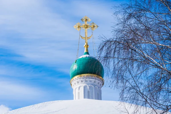 Dome with a cross of an old Orthodox church and a tree with bare branches