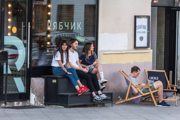 Rusya, Moskova, 20 Ağustos 2019 - Gençler sokakta kuaförün yanında oturuyorlar