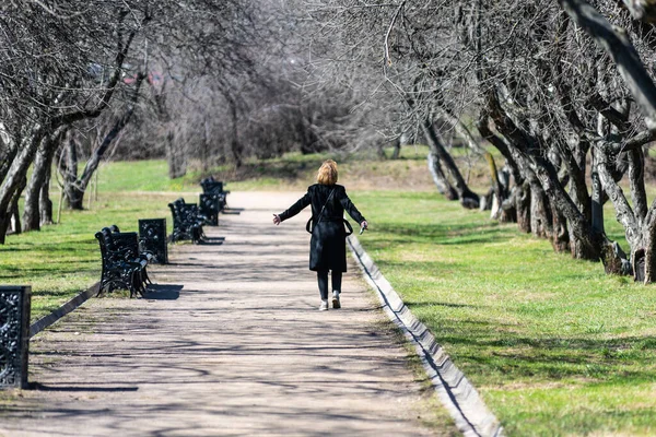 幸せな女性は春の公園を歩き 女の子は庭の道に沿って行きます — ストック写真