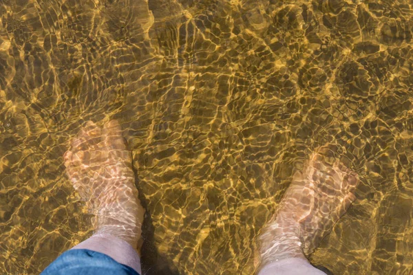 男人的脚在沙滩上的水里 — 图库照片