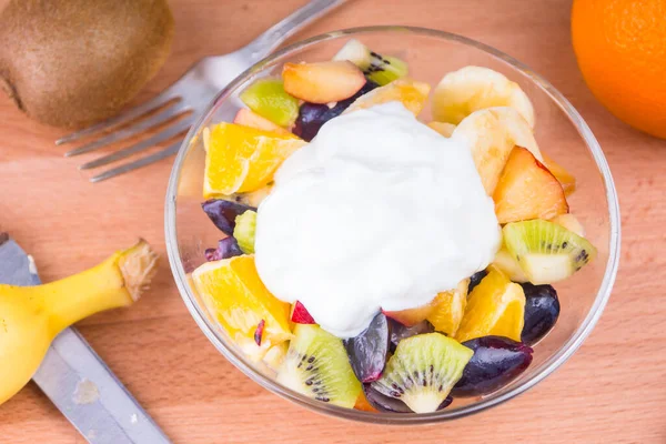 Delicious fruit salad with Greek yoghurt on a wooden table - fruit diet