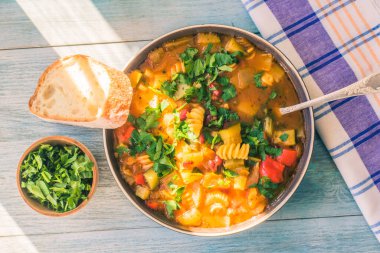 İtalyan sebze çorbası, makarna ve yeşil maydanozla boyalı ahşap bir masada yakın plan bir peçete manzaralı bir tabakta.