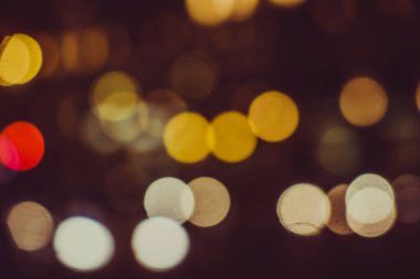 Gece şehir sokaklarının arka planında parlak araba farları var.